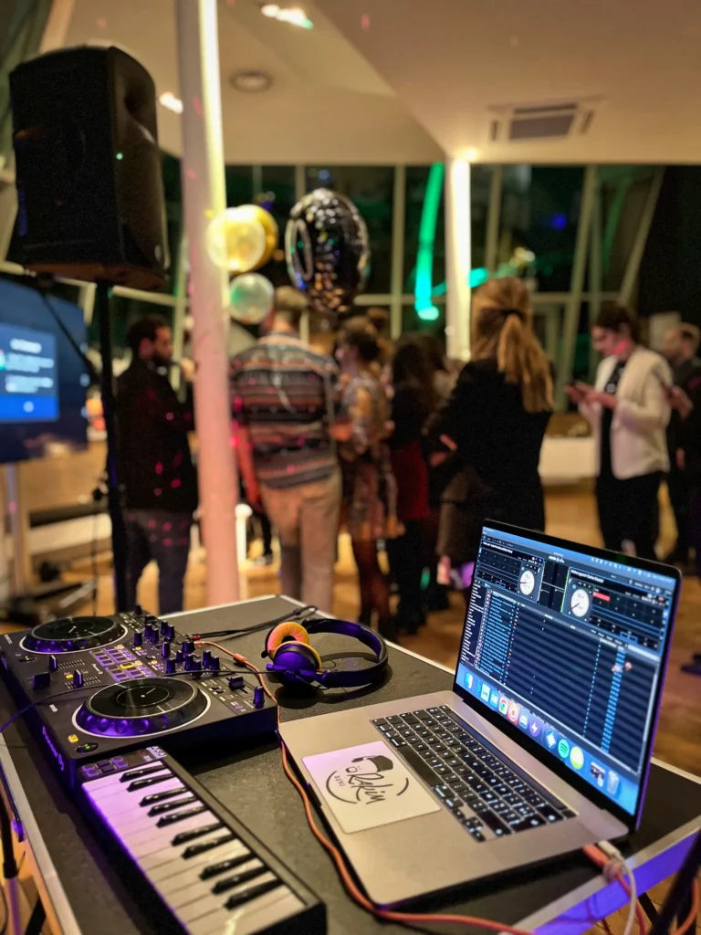 Dj equipment on a table in front of a crowd of people.
